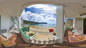 A beach view from a balcony with a white railing, a staircase, and a sign indicating a sanitary area. - CHOLSON CHALETS LIMITED (Charlotteville)