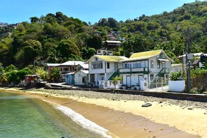 A beachfront property with a prominent building featuring a green staircase and a sign indicating a restaurant. - CHOLSON CHALETS LIMITED (Charlotteville)