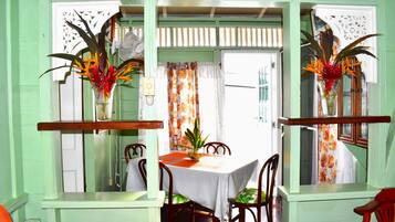 A dining area with a table set for two, flanked by chairs, and a window with a curtain.