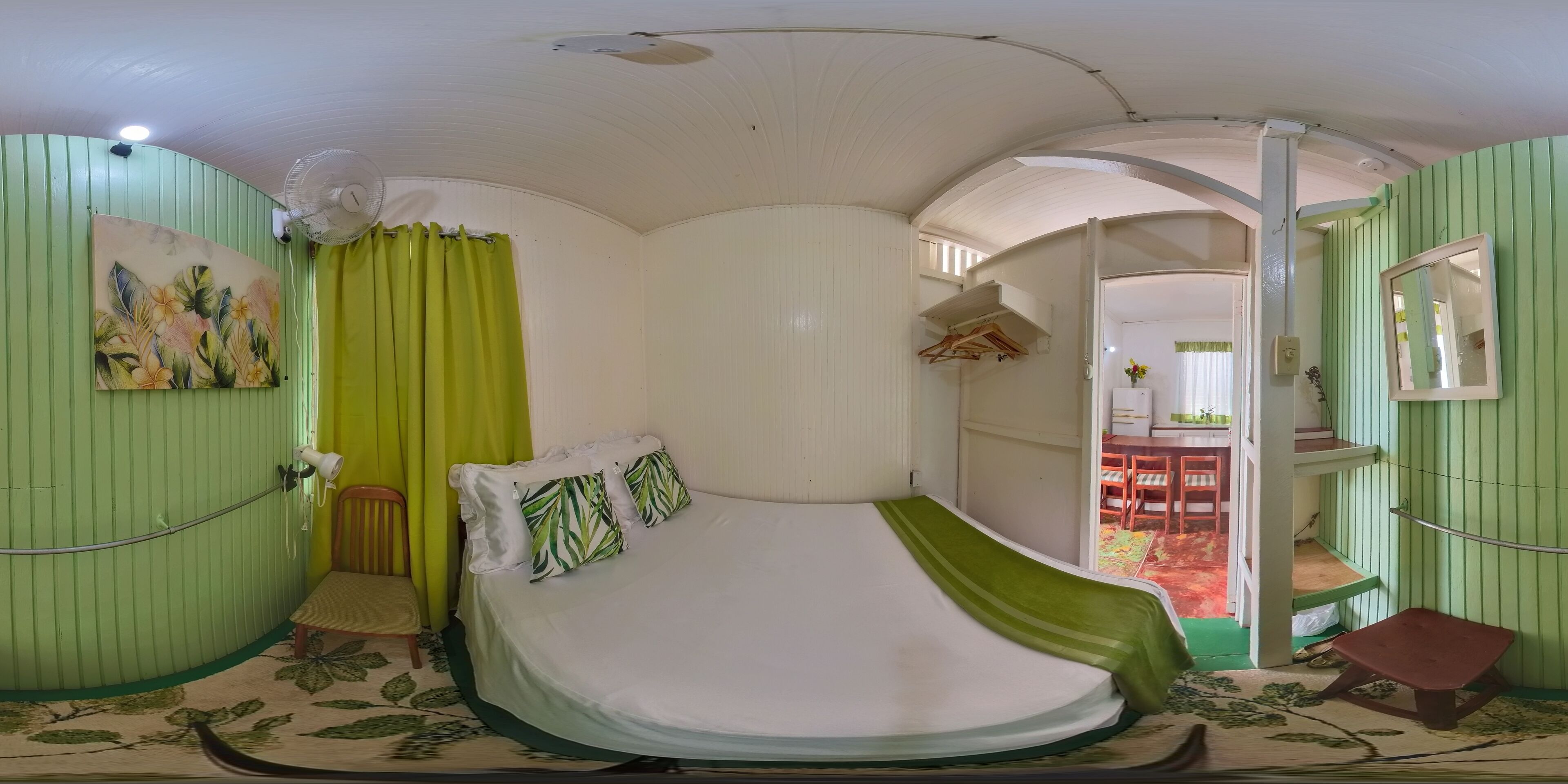 A room with a bed, a chair, a table, and a mirror.