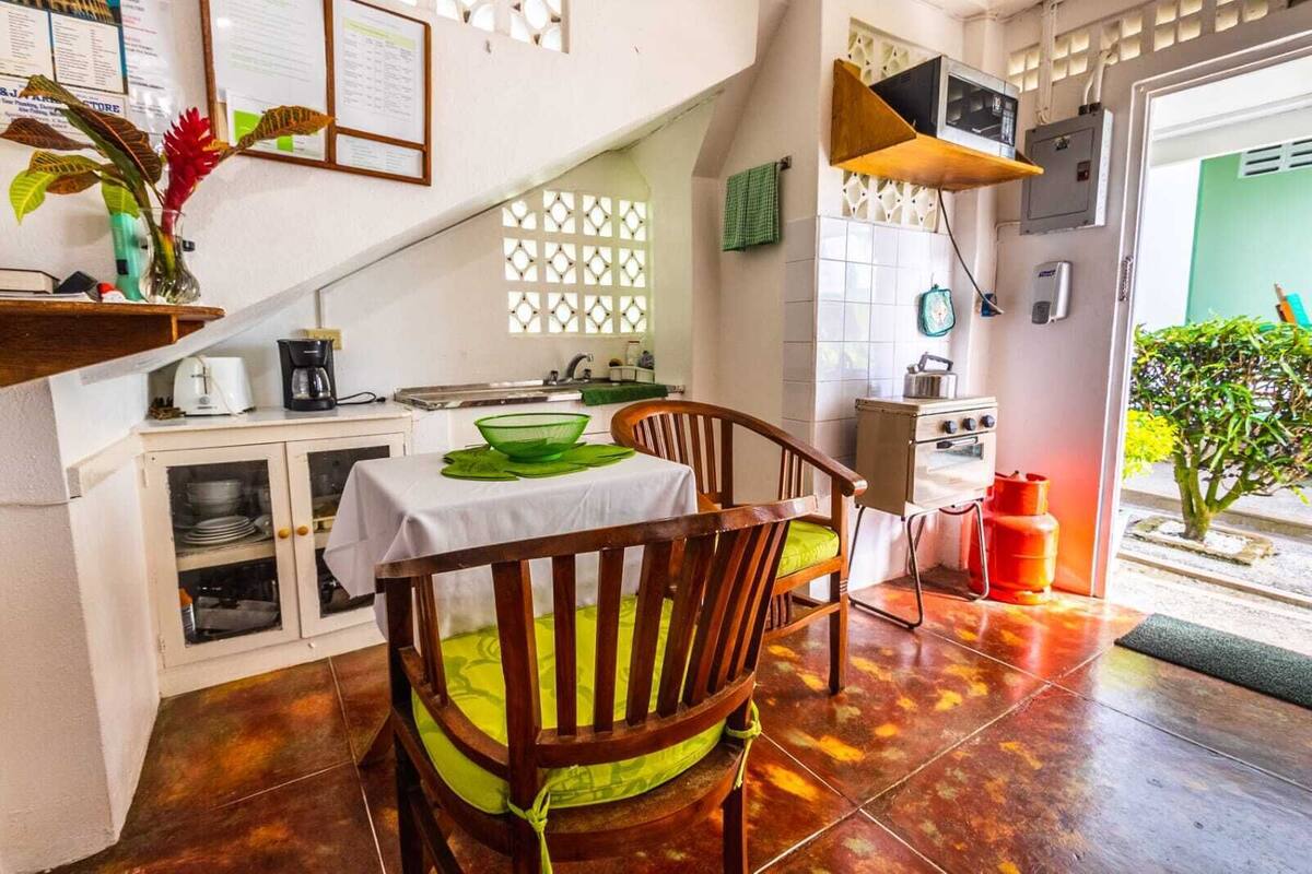 A compact kitchen with a dining area, including a table, chairs, and a small oven.