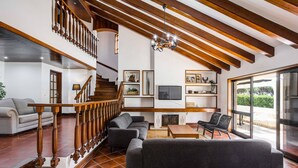 Ein großzügiger Wohnbereich mit Treppe, einer Couch, einem Fernseher und einem Kamin.