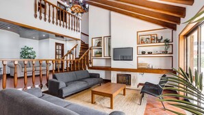 Ein großzügiger Wohnbereich mit grauem Sofa, einem Holztisch und einer Treppe mit Holzbalken.