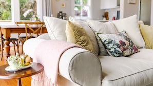 Una sala de estar con un sofá blanco, una mesa de centro de madera y un comedor con mesa y sillas de madera.