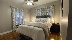 Ein Schlafzimmer mit einem großen Bett, einem Deckenventilator und Vorhängen.