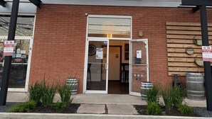 Das Äußere der New Braunfels Brewing Company mit einem Schild über dem Eingang, einer Ziegelaußenwand und einer Glastür.