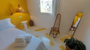 Une chambre d’hôtel avec un lit, une petite table, une chaise, une fenêtre et un miroir.