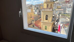 Une pièce dotée d’une fenêtre donnant sur un paysage urbain, avec une tour imposante et des bâtiments très rapprochés les uns des autres.