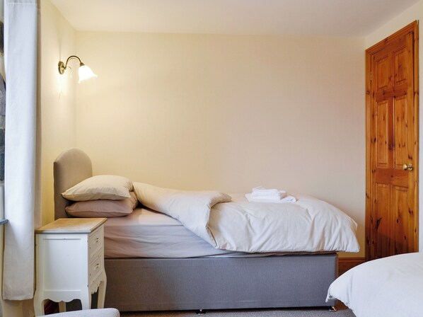 Un lit bien fait, avec du linge de lit blanc, une table de chevet avec une lampe et une porte en bois.