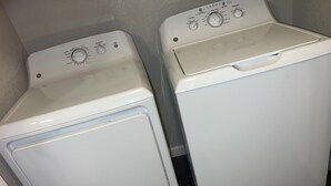 Dos lavadoras blancas de carga frontal, una al lado de la otra, en un cuarto de lavado.