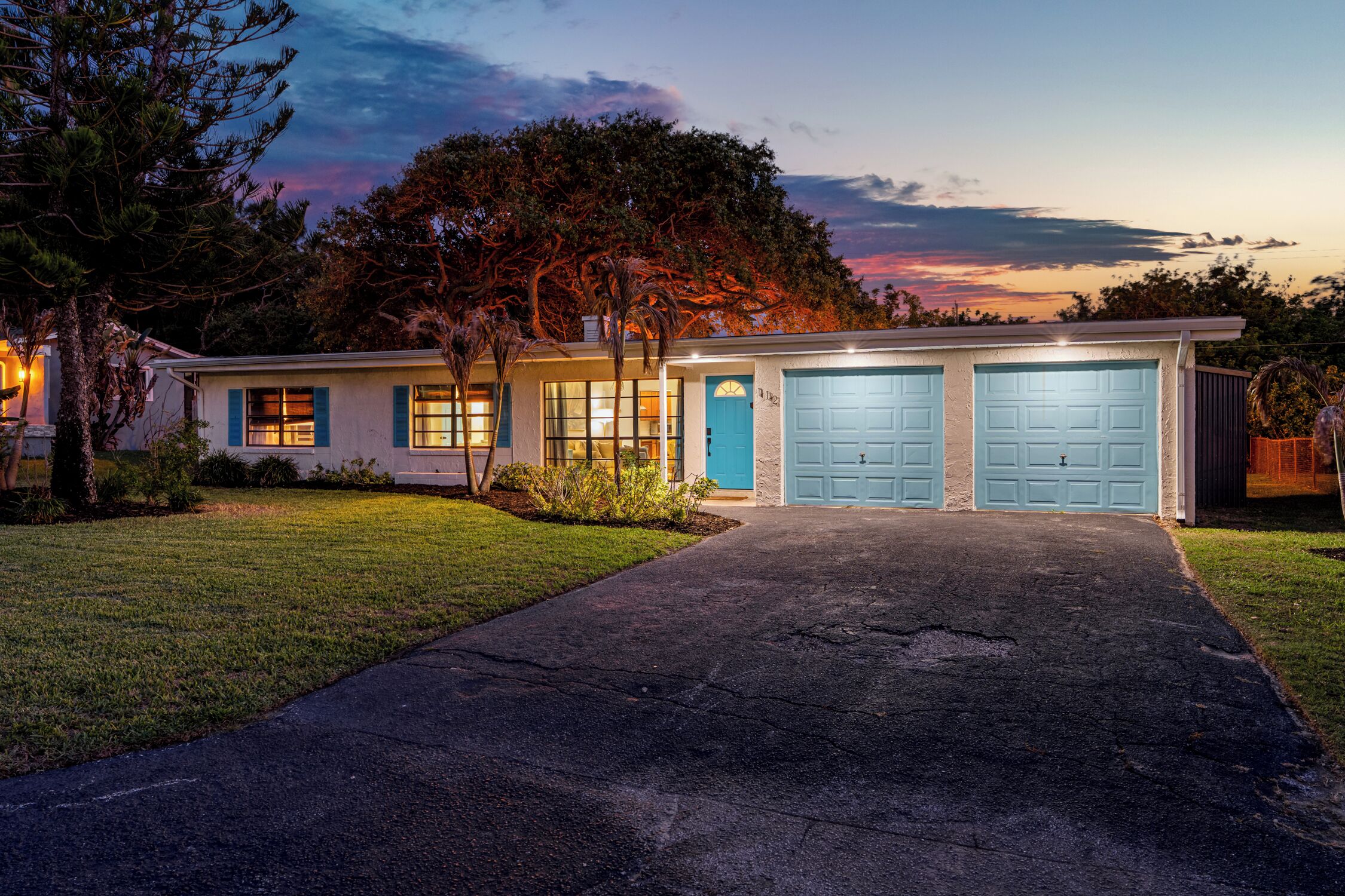 A two-story house with a driveway, garage doors, and a lawn.