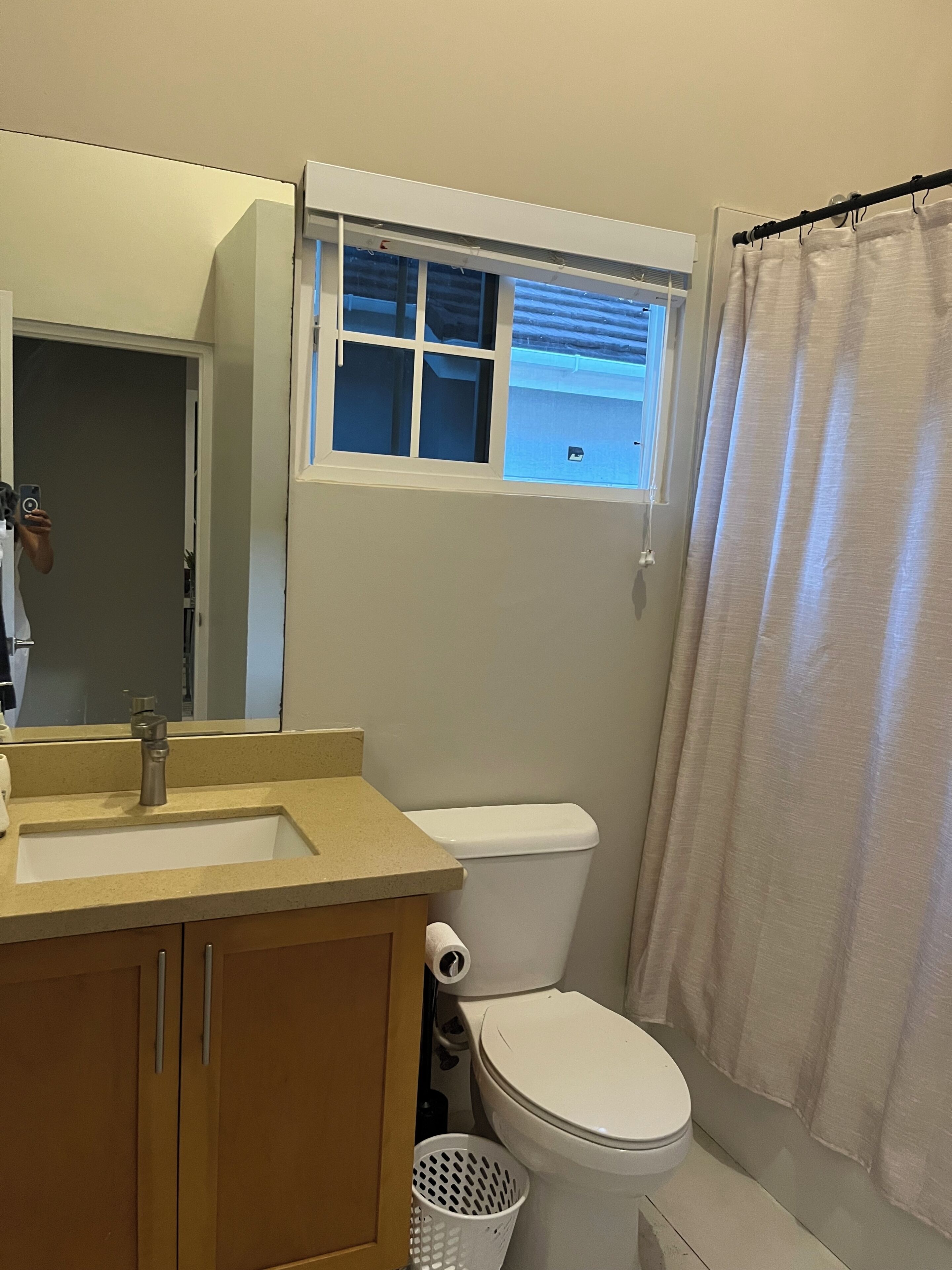 A bathroom with a sink, toilet, and window.