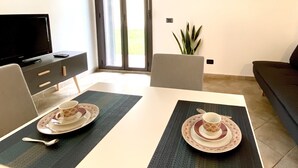 Una sala de estar moderna con televisor, una mesa de comedor con dos juegos de vajilla, un sofá y un ventanal con vistas.