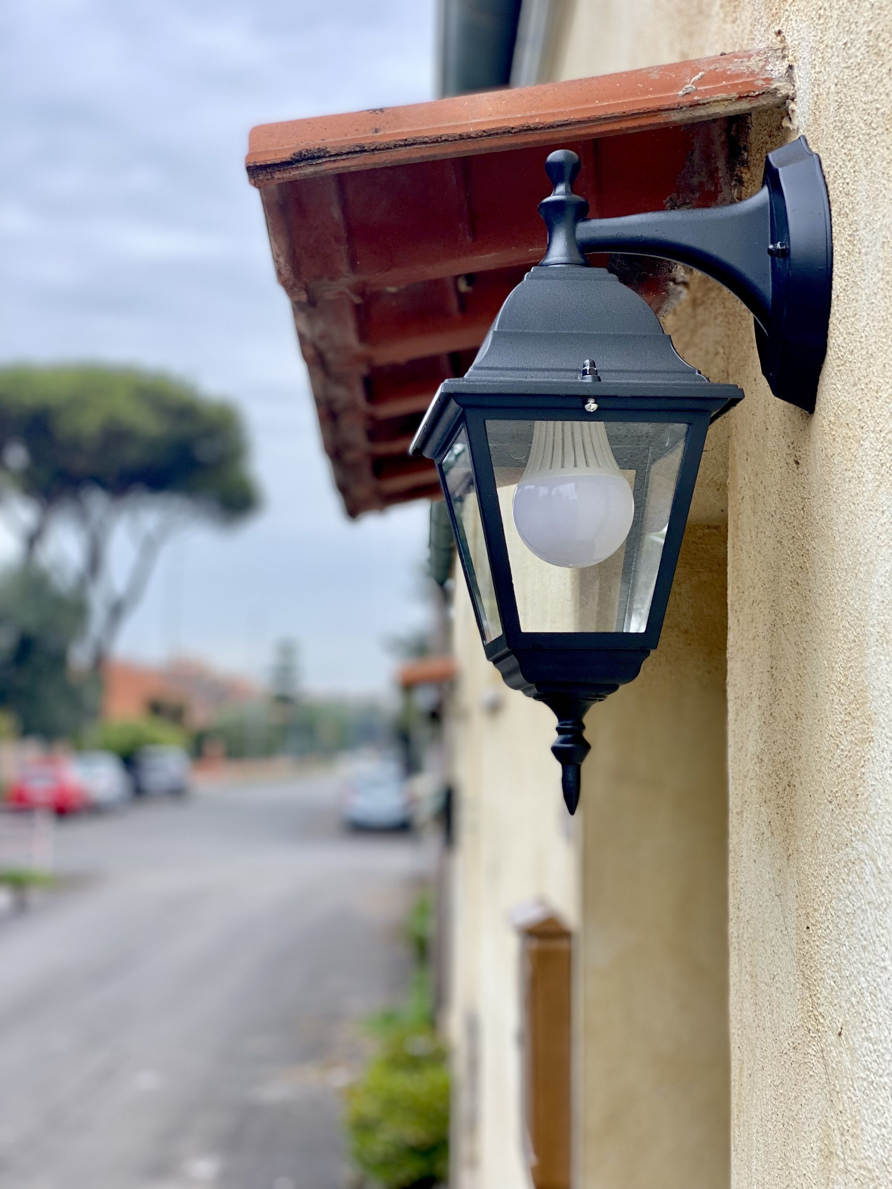 A black outdoor wall-mounted light fixture with a clear glass cover and a visible bulb.