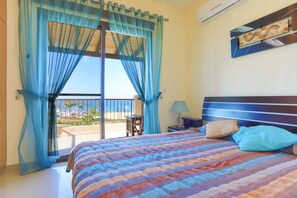 A bedroom with a bed, a nightstand, a lamp, and a view of the outdoors. - Villa Arbanassi Latchi, beach, pool, A/C, WiFi, garden, views (Latchi Beach)