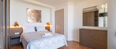 A bedroom with a bed, bedside tables, a wardrobe, a mirror, and a decorative wall piece.