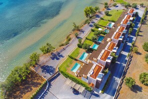 Vista aérea de un hotel costero con varias piscinas, un estacionamiento y una playa.