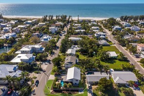 An aerial view of a coastal residential area with houses, a swimming pool, and a beach in the background. - The Laguna Beach: 2 Blocks to Beach, Pool, 5 Hole Put Put, Foosball, Cornhole by Anna Maria Life (Anna Maria)