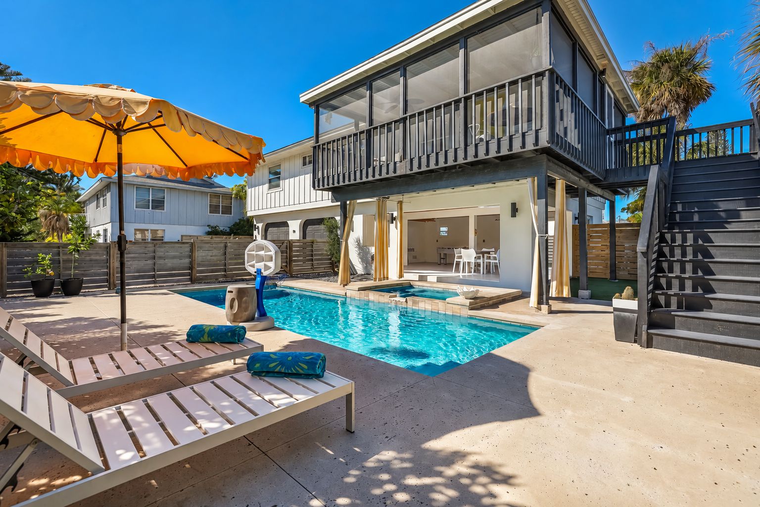 A residential property with a swimming pool, outdoor seating, and a covered patio area.