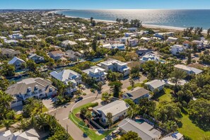 An aerial view of a coastal residential area with houses, a beach, and a marina.