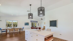 Cozinha ampla com ilha central, piso de madeira e iluminação pendente.