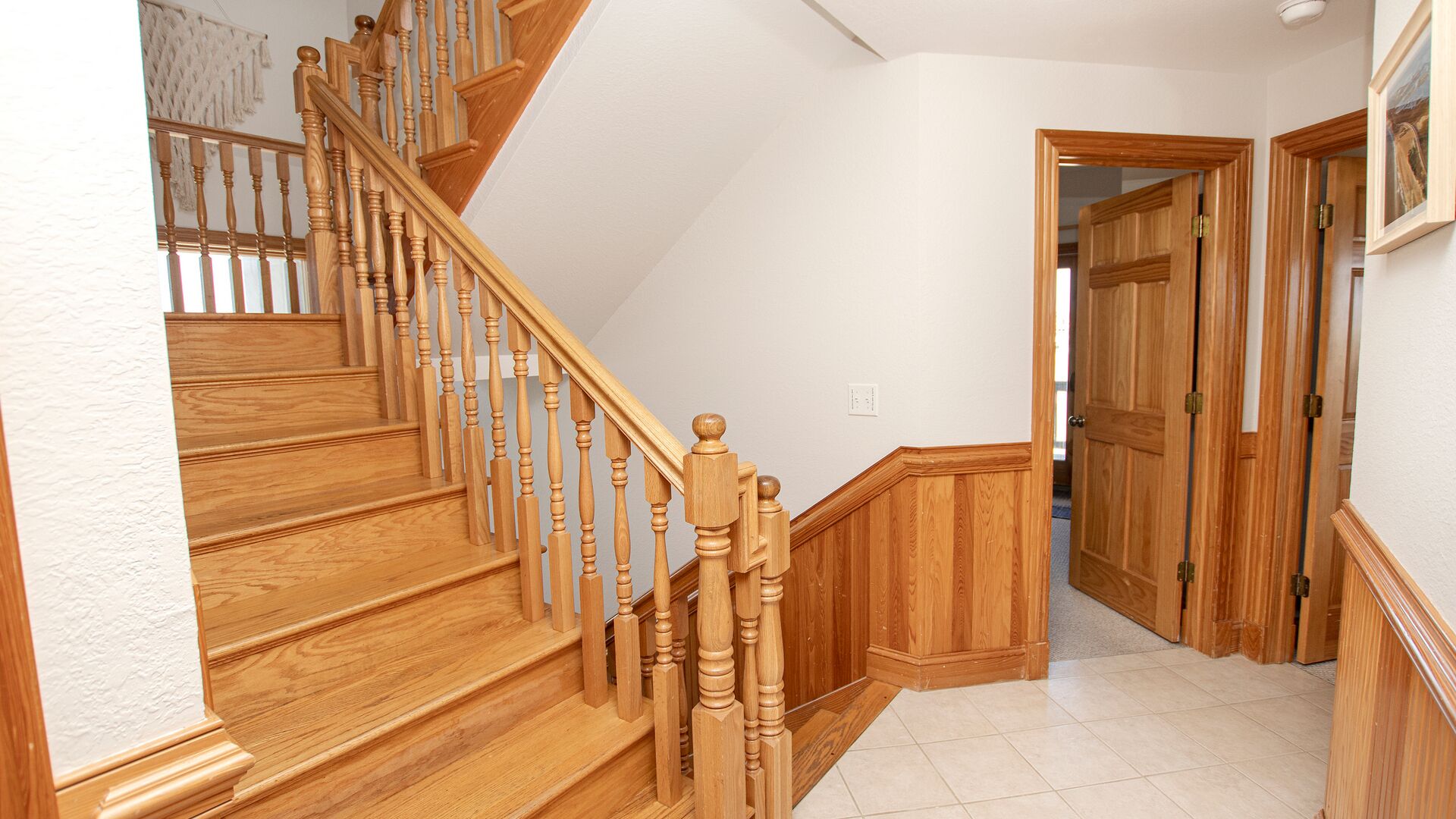 A wooden staircase with a handrail, leading to a landing with a door.