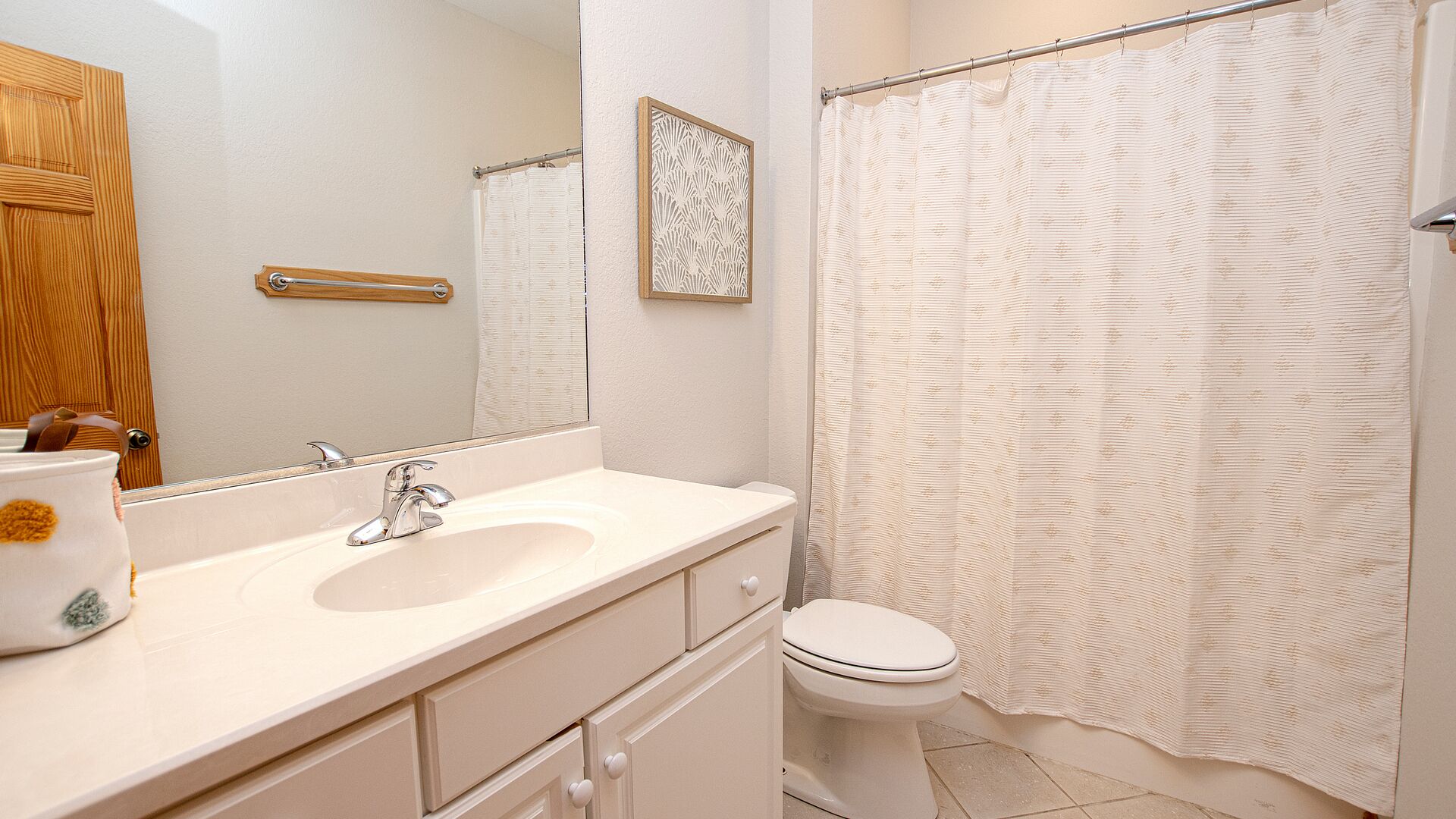 Une salle de bain équipée d’un lavabo, d’un miroir, de toilettes et d’un rideau de douche.