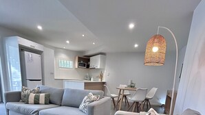 Una sala de estar moderna con un sofá gris, una mesa de centro de madera y una zona de comedor con mesa y sillas.