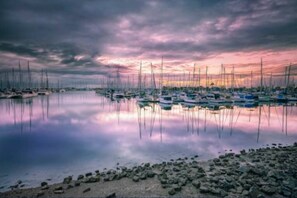 A marina with numerous boats docked, calm water, and a rocky shoreline. - When size does matter!! and a great location to (Manly)