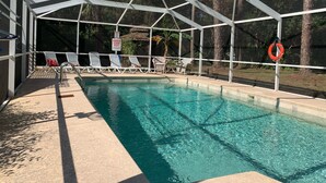 A covered swimming pool with clear water, surrounded by lounge chairs and a lifebuoy. - Nature Coast Inn and Cottages (Inglis)