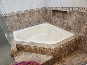 A bathroom with a freestanding bathtub, tiled walls, and a decorative border. - Casa Escondida Alajuela (Alajuela)