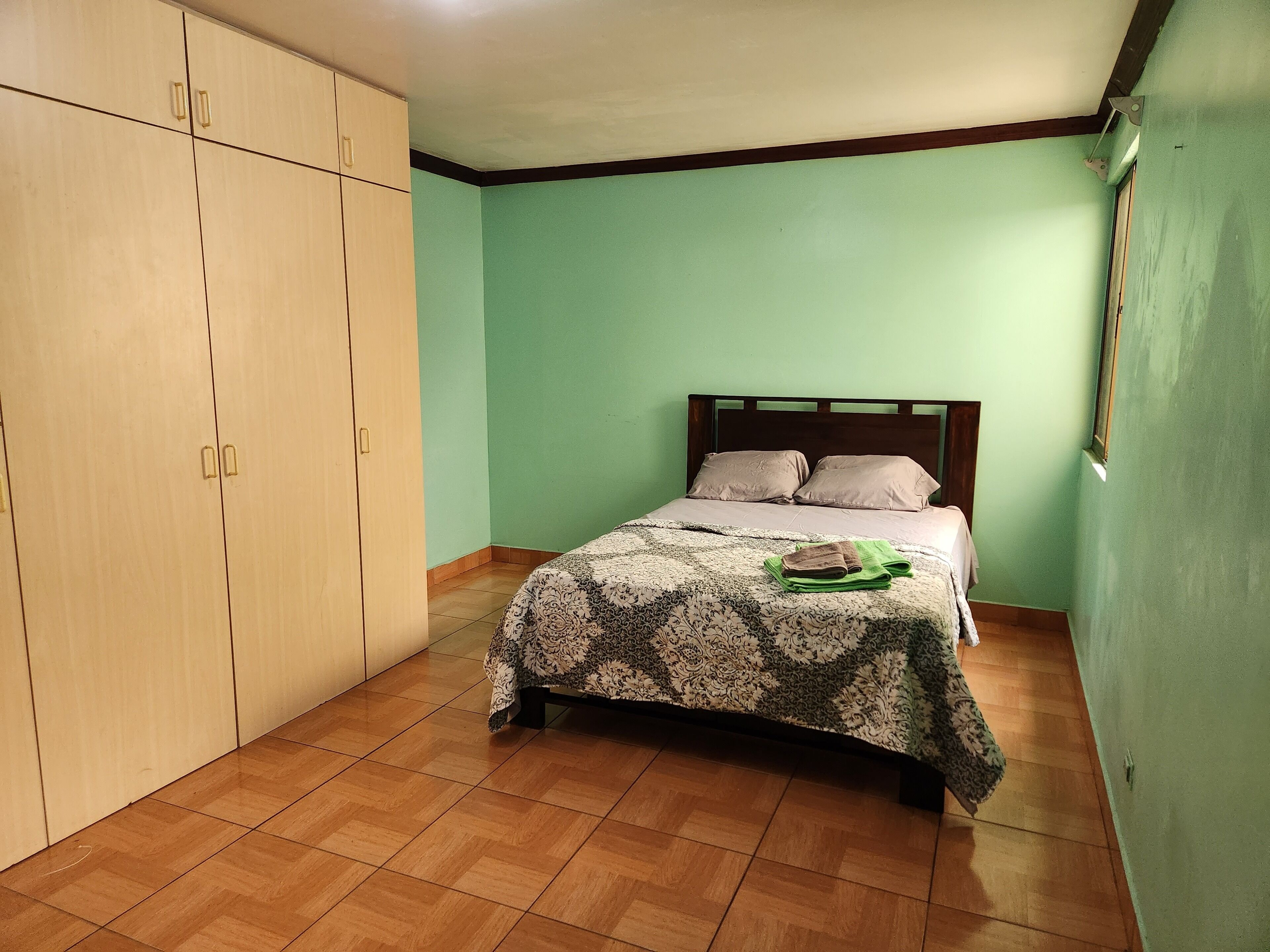 A bedroom with a bed, a wardrobe, and a green wall.