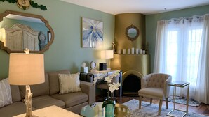 A living room with a sofa, armchair, coffee table, and fireplace.