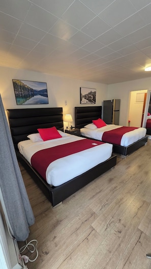 A hotel room with two beds, a nightstand, a lamp, and two framed pictures on the wall. - Mountain View Hope Motel (Hope)