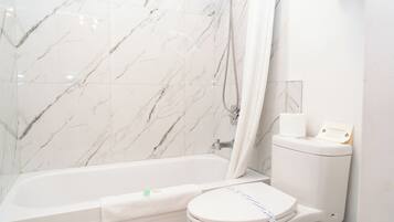 A bathroom with a bathtub, toilet, and marble walls.