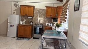 A kitchen with wooden cabinets, a refrigerator, an oven, and a table covered with plastic.