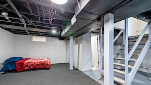 Een kamer met een bed, een trap en een deur naar een andere ruimte.