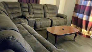 Een modulaire bank met een houten salontafel in een woonkamer met gestreepte gordijnen.