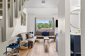A modern living room with a sofa, coffee table, and a view of the outdoors.