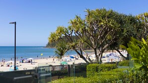 Une plage avec des palmiers, des parasols et des gens.