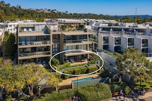 A modern multi-story residential building with balconies, a swimming pool, and lush greenery. - Apartment 03 Noosa Court  (Noosa Heads)