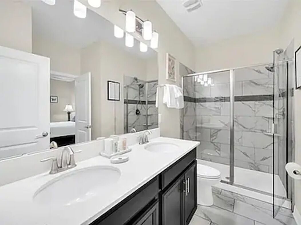 Une salle de bain moderne avec deux lavabos, un grand miroir et une douche à l’italienne.