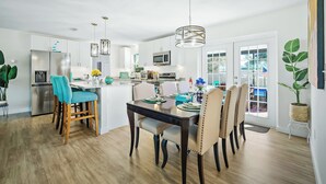 Una cocina moderna con una isla central, sillas de madera y una mesa de comedor para cuatro.