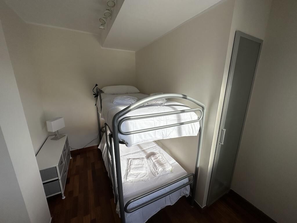Een stapelbed in een kleine kamer, met een bureau en een lamp.