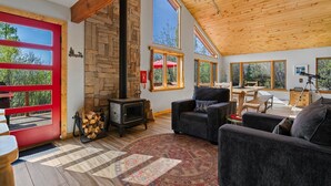 A cozy living room with a stone fireplace, large windows, and a high wooden ceiling. - Secluded Getaway Near Purgatory - Luxurious Hot Tub, Idylic 360° Views, Pets OK! (Durango)