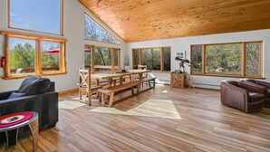 A spacious room with large windows, a wooden ceiling, and a wooden dining table. - Secluded Getaway Near Purgatory - Luxurious Hot Tub, Idylic 360° Views, Pets OK! (Durango)