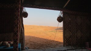 A room with a view of a desert landscape through an open doorway.
