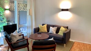 Una sala de estar acogedora con un sofá, dos sillones, una mesa de centro y un televisor.