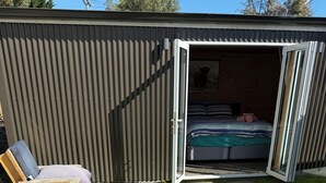 Una construcció petita i oberta, amb un llit i una zona de dormir visibles per la porta oberta.