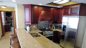 A kitchen with dark wooden cabinets, a stainless steel refrigerator, and a granite countertop.